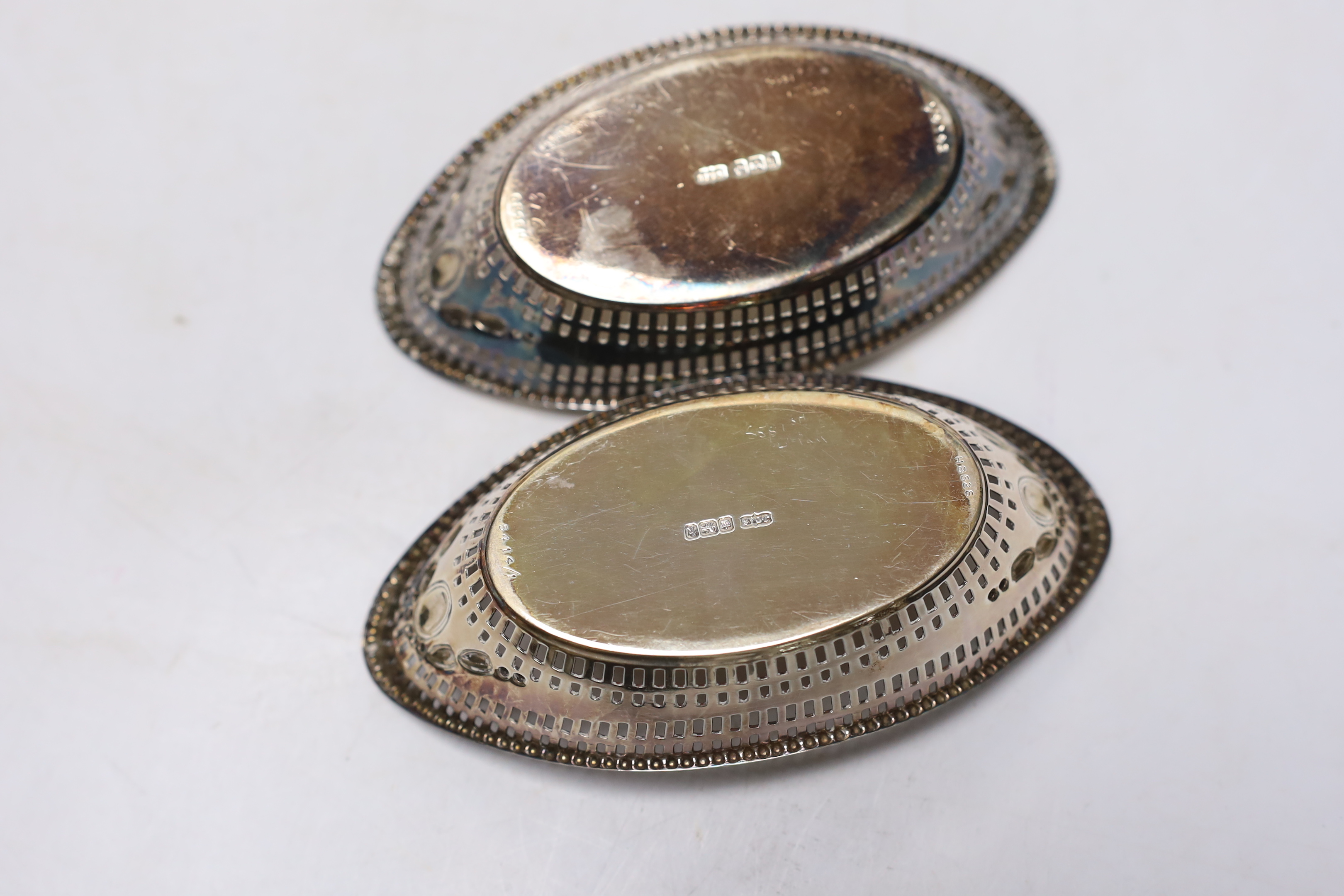 A George V silver sauceboat, Thomas Bradbury & Sons, Sheffield, 1919 and a pair of earlier pierced silver oval bonbon dishes, 13.8cm, 11.3oz.